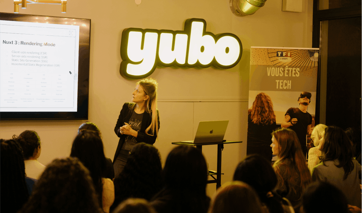 A woman is giving a presentation in front of a glowing Yubo sign